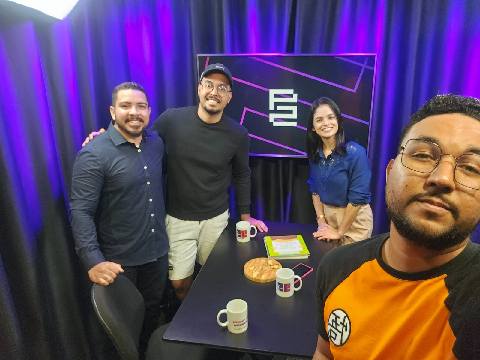 Convidados e equipe em volta da mesa da 95, com o símbolo no telão